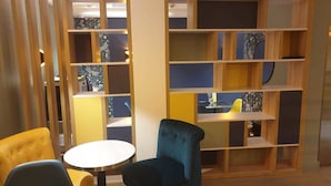 A modern interior with a wooden bookshelf, a round table, and two chairs. - Panam Hotel (Paris)