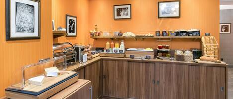 A breakfast bar with various food items and condiments, framed pictures on the walls, and a wooden counter.