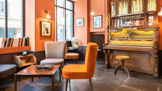 Una habitación acogedora con un piano, un ventanal grande y una zona de estar con una mesa y sillas.