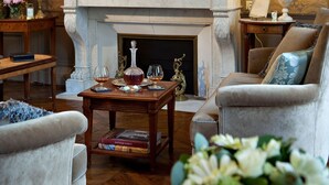 A traditional living room with a fireplace, a large mirror, and classic furniture.