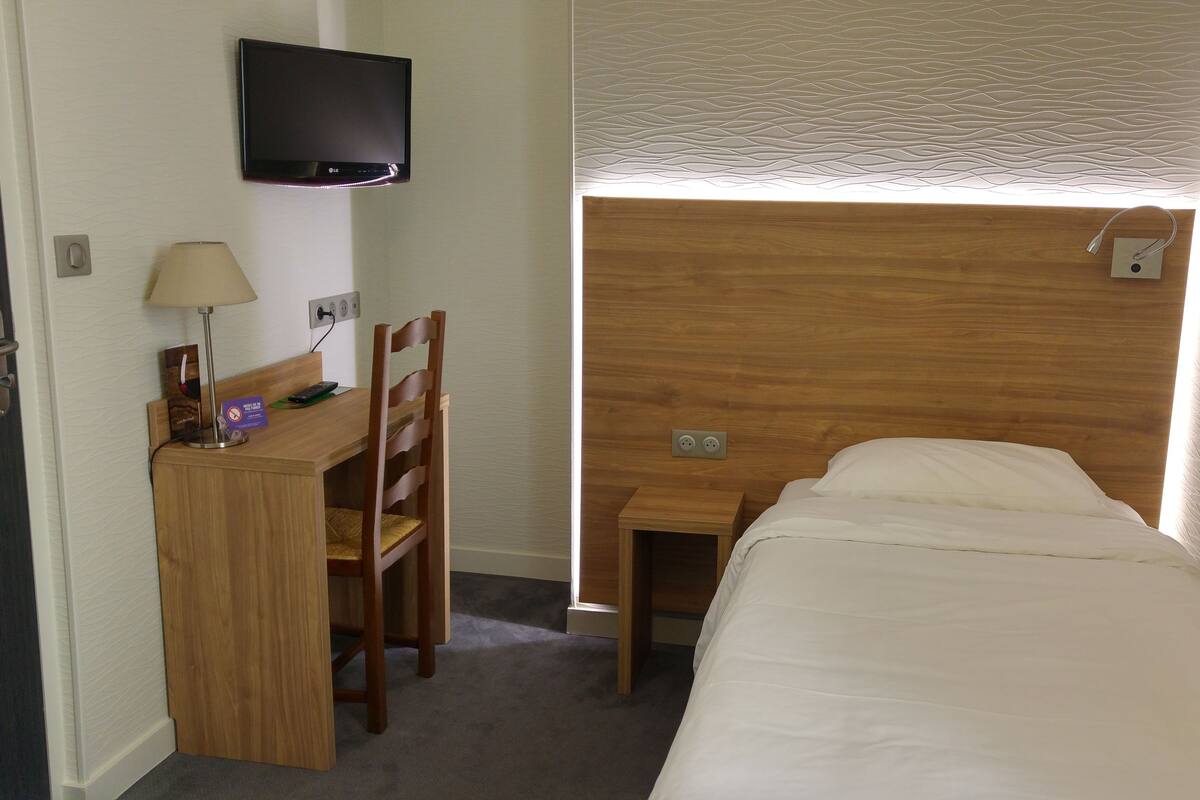 Una habitación de hotel con escritorio de madera, silla y cama.