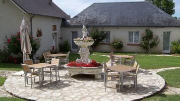 A patio with stone flooring, a central fountain, and outdoor furniture.