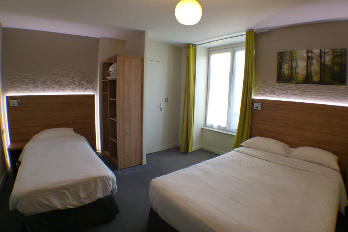 Habitación de hotel con dos camas, un armario, una ventana con cortinas y un cuadro en la pared.