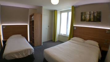 Een hotelkamer met twee bedden, een kledingkast, een raam met gordijnen en een schilderij aan de muur.