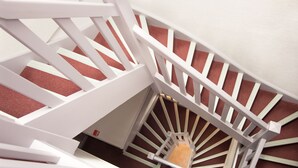 Una escalera blanca con un rellano alfombrado de rojo.