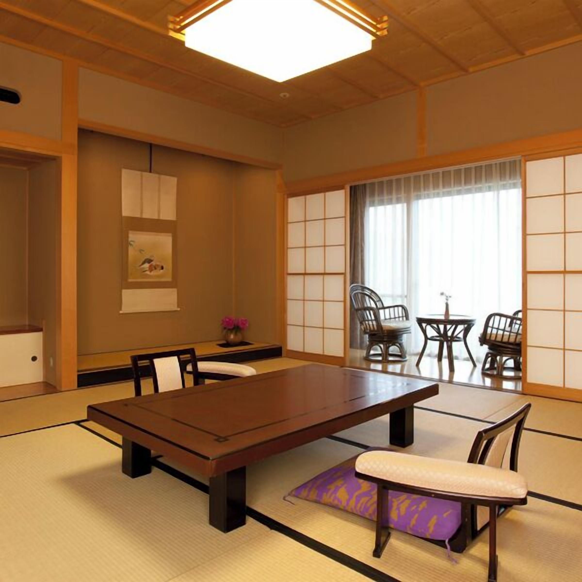 Una habitación japonesa tradicional con suelo de tatami, una mesa baja y puertas correderas shoji.