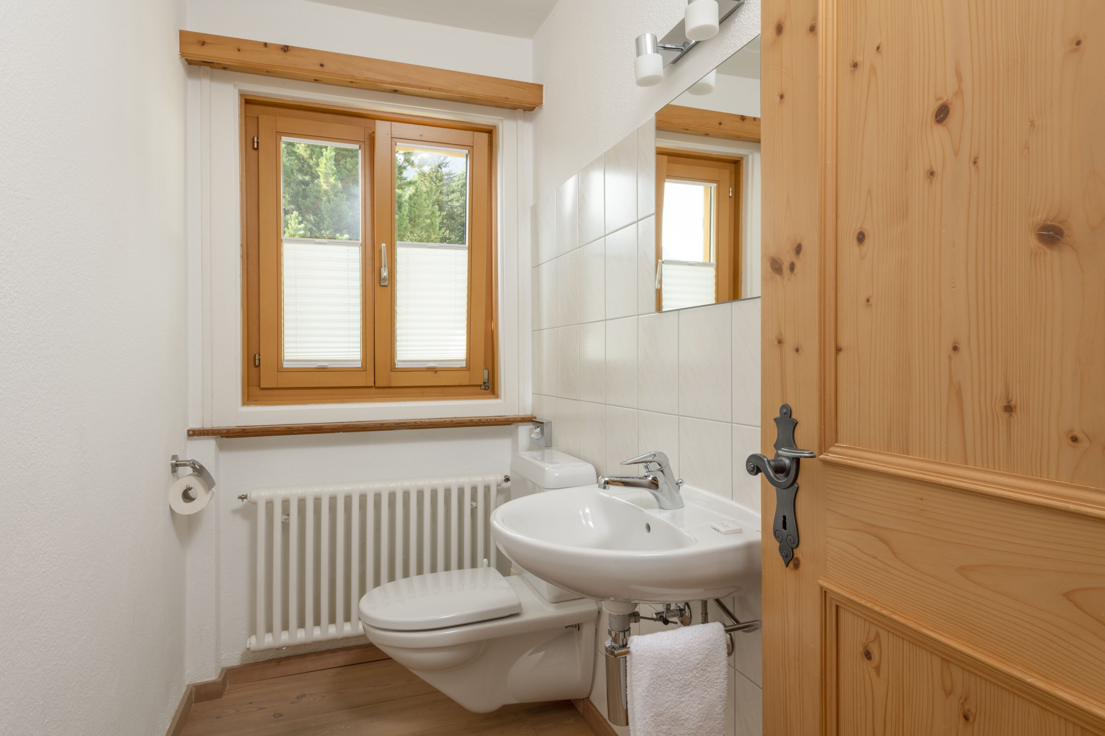 A small, clean bathroom with a toilet, sink, and window.
