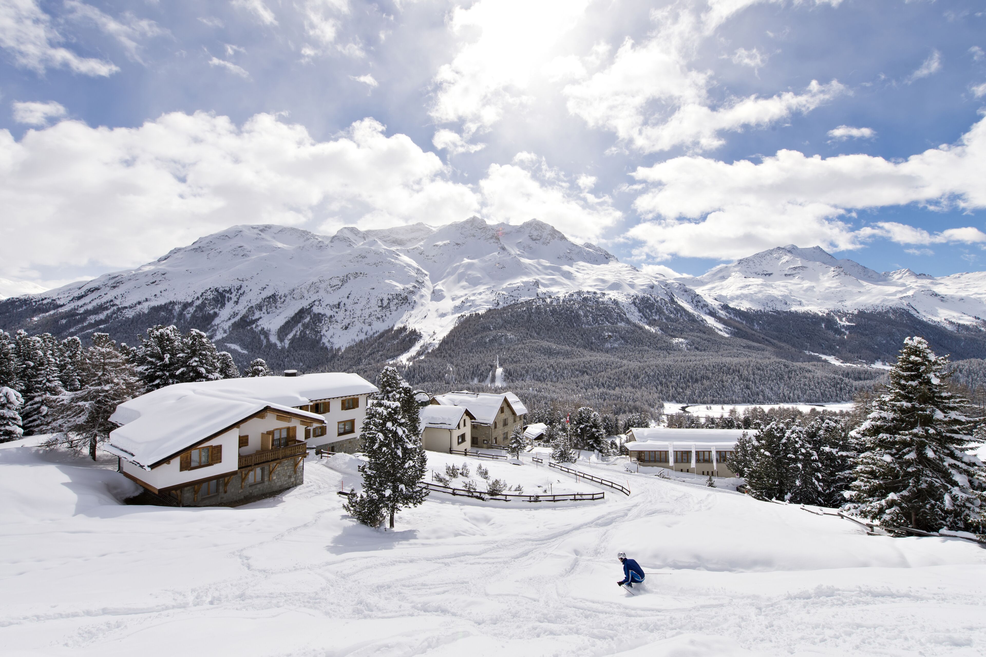 A snow-covered mountain resort with wooden cabins and a ski slope.