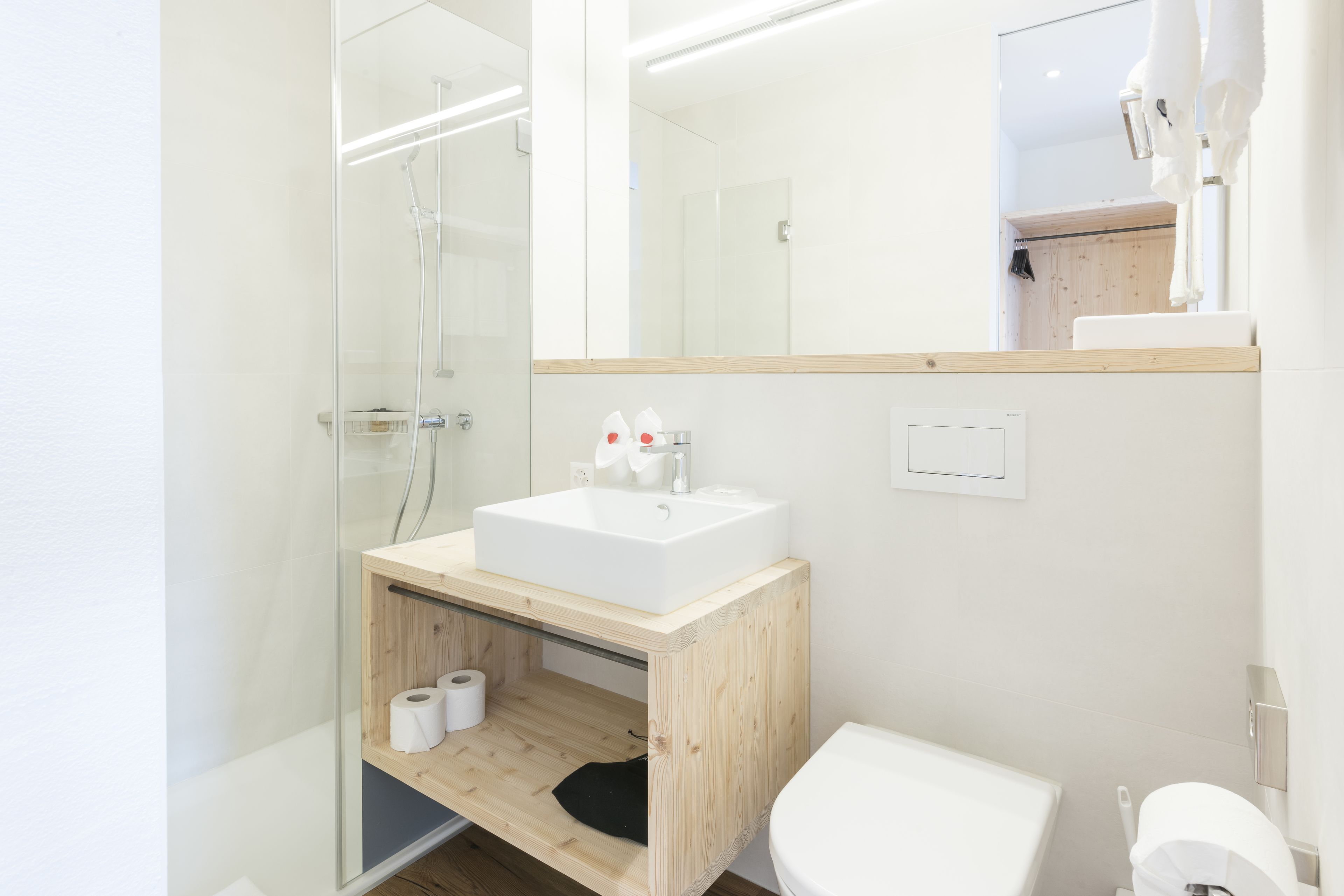 A modern bathroom with a glass-enclosed shower, a wooden vanity with a sink, and a toilet.
