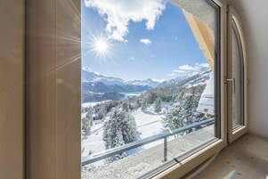 Una habitación con un ventanal grande que ofrece vistas a montañas nevadas y un cielo despejado.