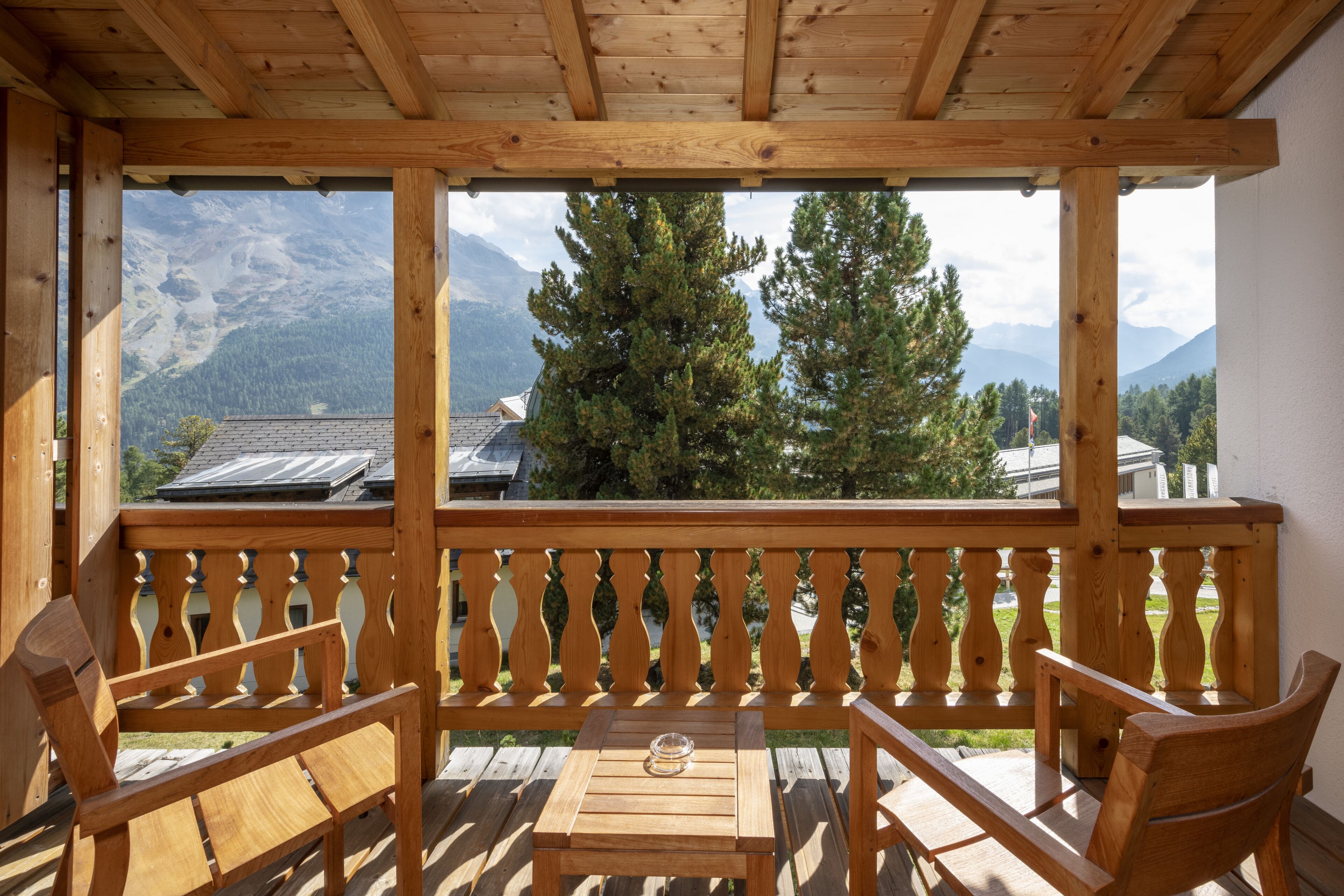 Eine Holzterrasse mit Blick auf Berge, einem Tisch und zwei Stühlen.