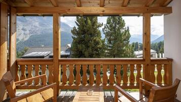 Eine Holzterrasse mit Blick auf Berge, einem Tisch und zwei Stühlen.