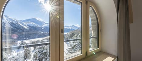 Una habitación con amplios ventanales que ofrecen vistas a montañas nevadas y un valle.