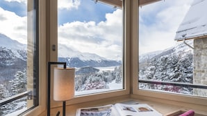 A room with a large window overlooking a snowy mountain landscape. - Berghotel Randolins (St. Moritz)