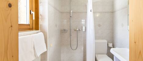 A bathroom with a shower, toilet, and sink.