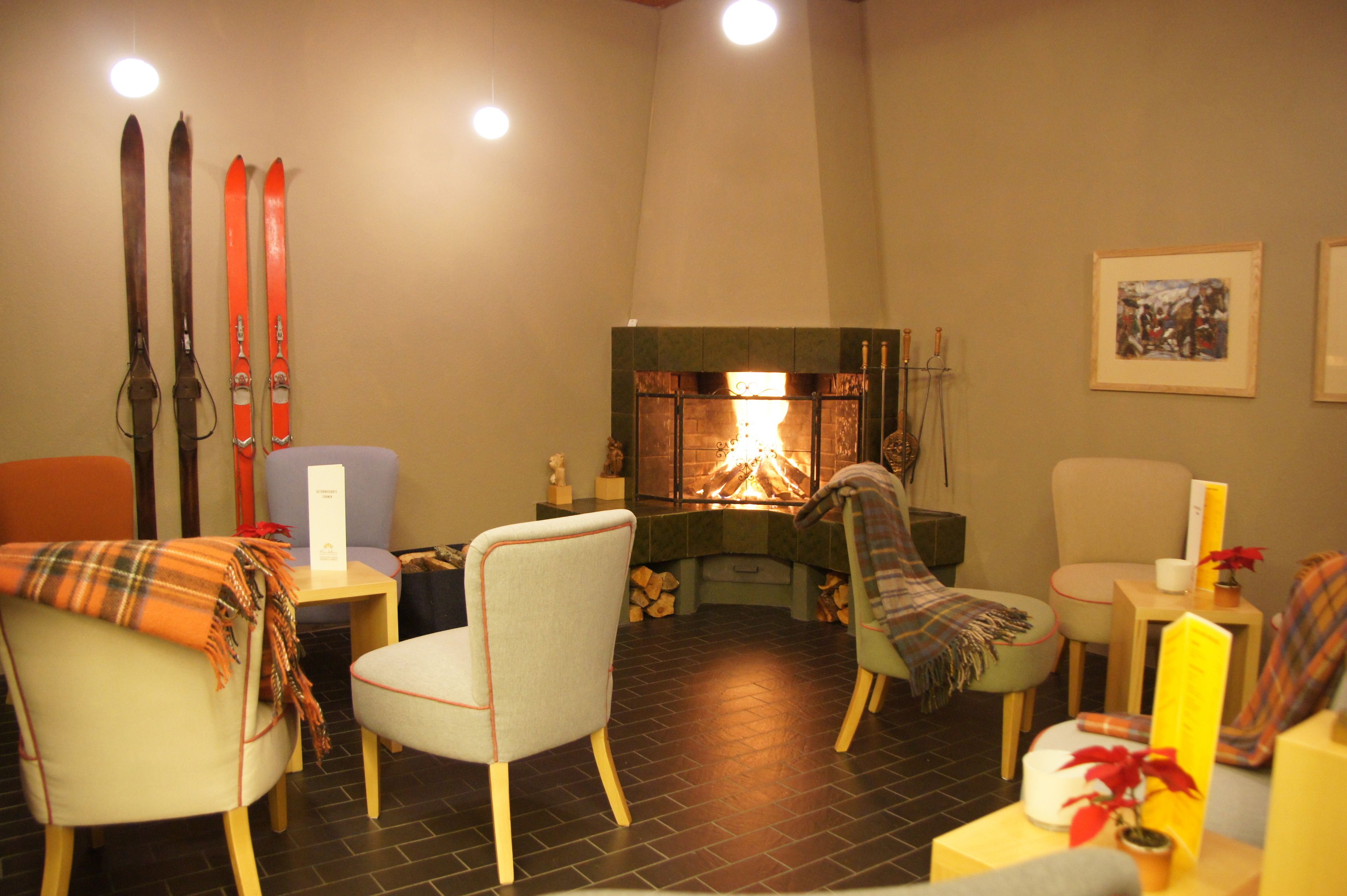 A cozy room with a fireplace, a chair, a table, and skis leaning against the wall.