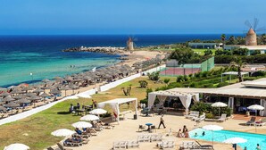 Un complexe hôtelier de bord de mer doté d’une piscine, de parasols et de chaises longues.