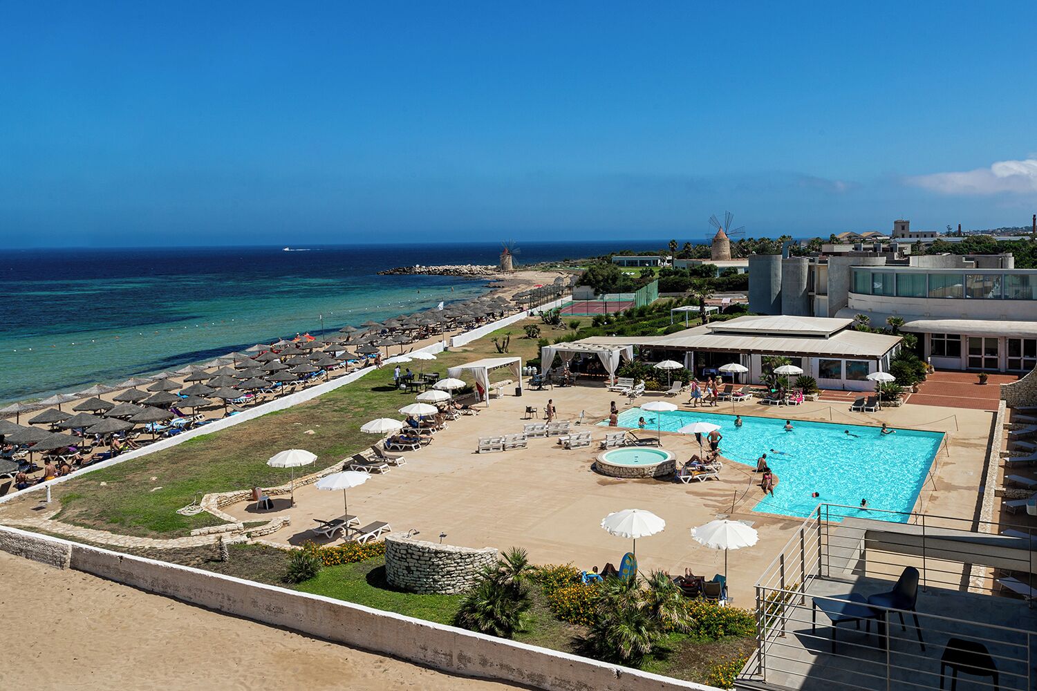 Un complexe hôtelier doté d’une piscine, d’une plage et offrant une vue sur l’océan.