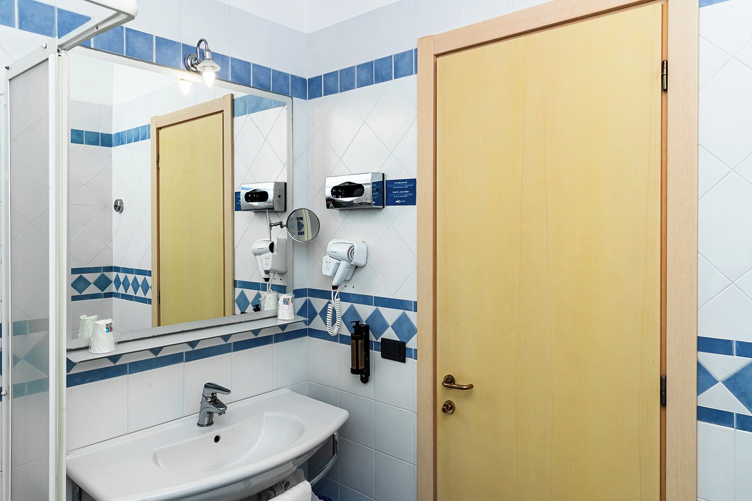 A bathroom with a sink, mirror, hairdryer, and towel rack.