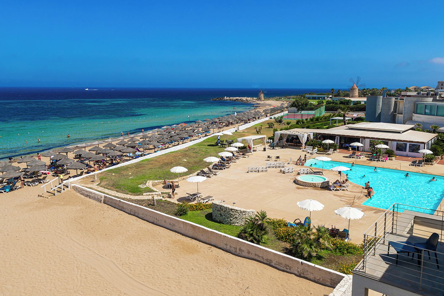 Un resort con playa, piscina y un molino.