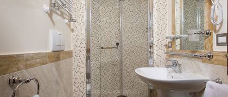 A bathroom with a shower, toilet, sink, and towel rack.