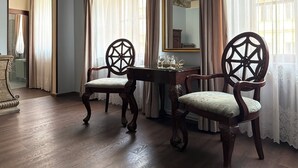 Una habitación con dos sillas de madera decorada, una mesa con cristalería y un espejo.