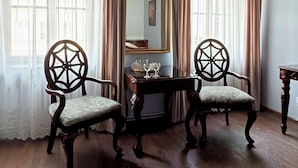Una habitación con dos sillas ornamentadas, una mesita, un espejo y un techo con detalles artísticos.