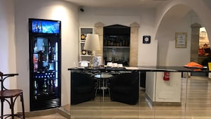 Un espace bar équipé d’un réfrigérateur rempli de boissons, d’un comptoir et de deux chaises noires.