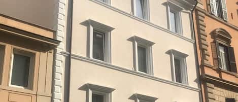 A multi-story building with a classic architectural style, featuring a row of windows on each floor and a ground-level entrance with a canopy.