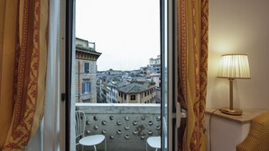 Un balcon avec deux chaises blanches, une vue sur le paysage urbain et une lampe sur une table.