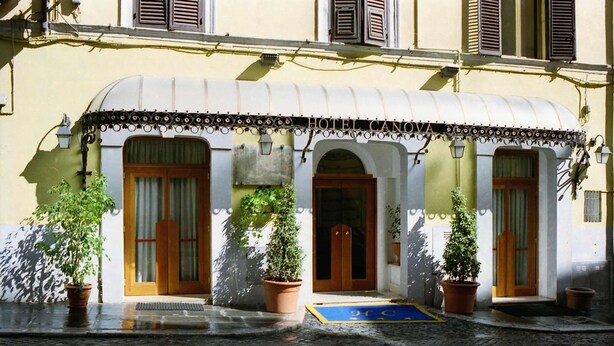 La façade d’un hôtel, avec un toit incurvé, des portes en bois et des plantes en pot.