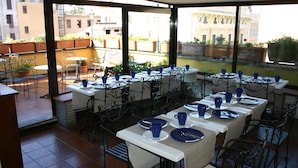 Un restaurant avec une terrasse, des tables blanches et des tasses bleues.