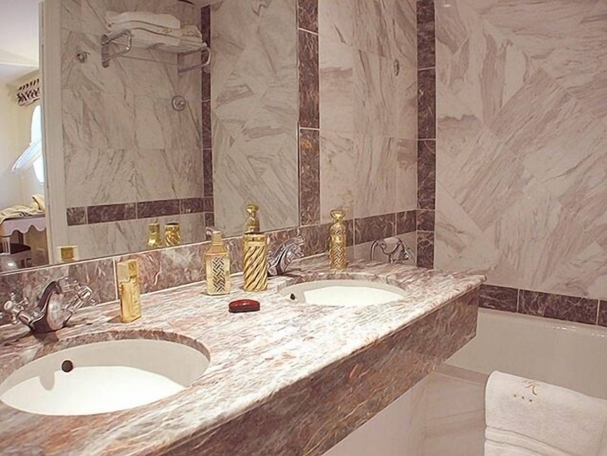 Une salle de bain avec deux lavabos, un grand miroir et des carreaux de marbre.