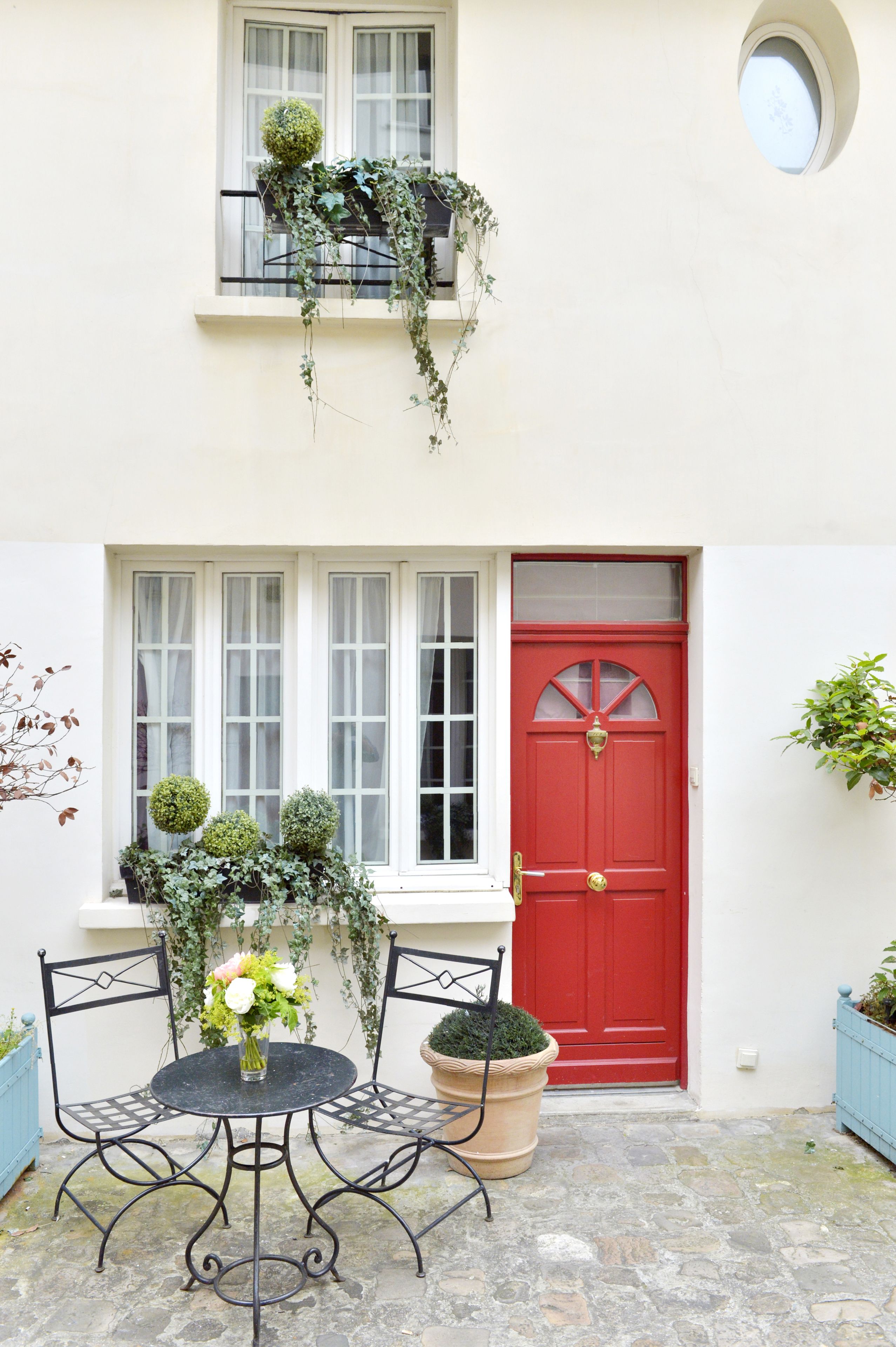 A red door, a white window, and a round window above the door.