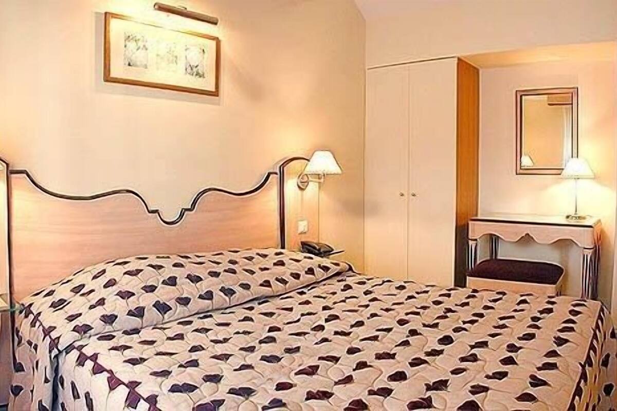 Ein Schlafzimmer mit Bett, Nachttischen, einem Kleiderschrank und einem Spiegel.