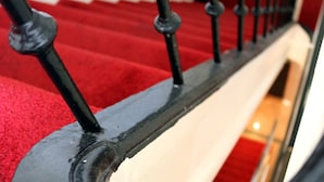 A close-up of a black metal staircase railing with a red carpeted floor. - Max Hotel Amsterdam (Amsterdam)