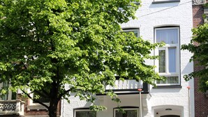 A hotel with a white facade, multiple windows, and a tree in front. - Max Hotel Amsterdam (Amsterdam)