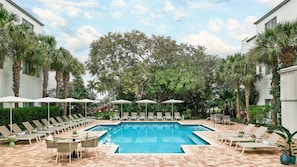 A pool area with lounge chairs and umbrellas, surrounded by palm trees and a large tree in the background. - Faro Blanco Resort Marathon Florida Keys, Curio by Hilton (Marathon)