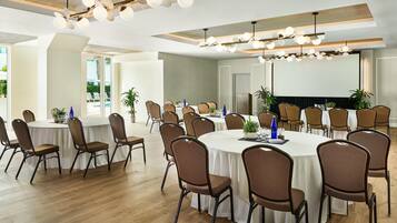 A conference room with round tables, chairs, and a large screen.