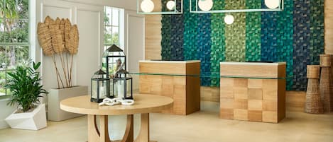 Un interior moderno con una mesa redonda de madera, dos mesitas auxiliares con superficie de vidrio y una pared con textura.