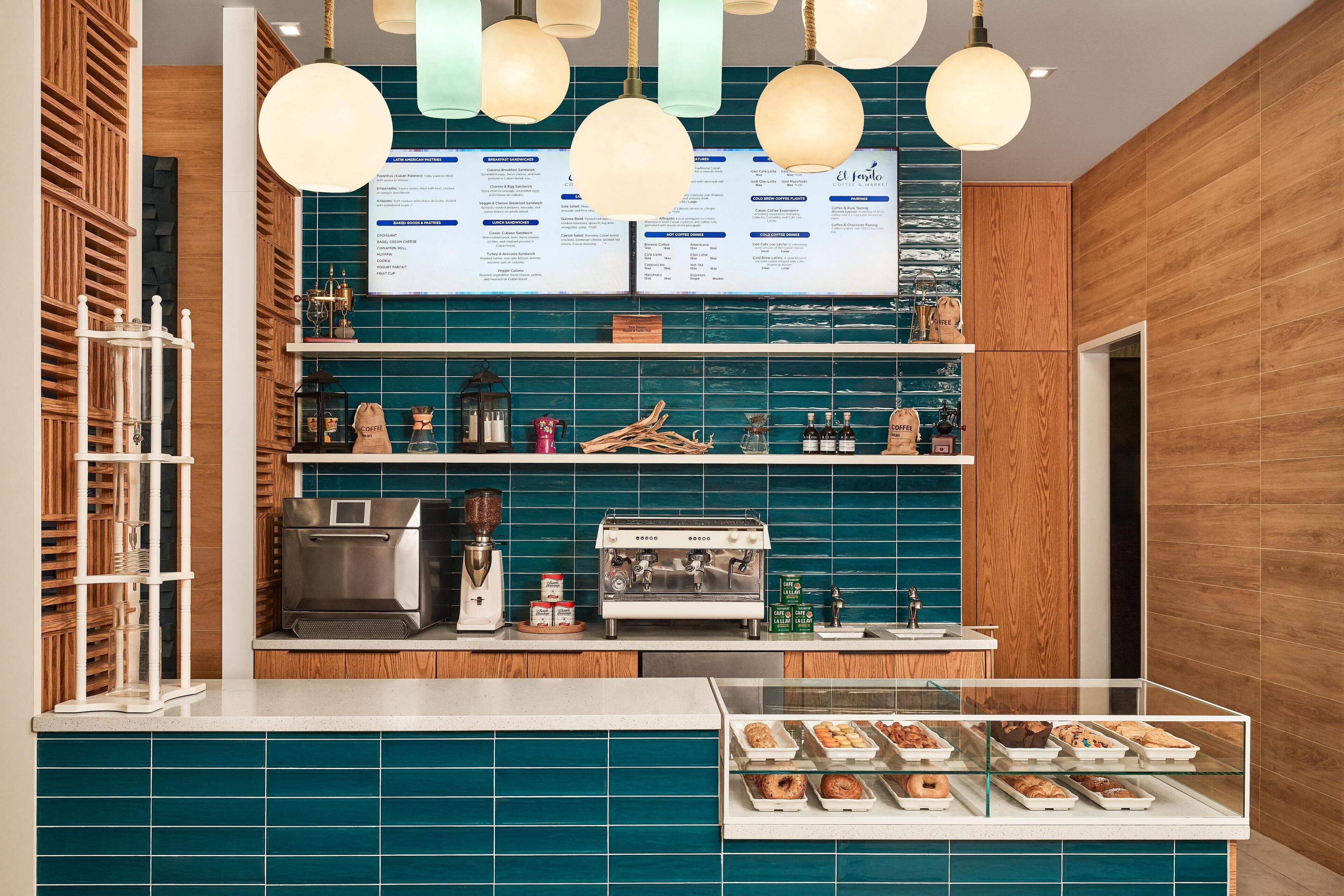 A coffee shop interior with a menu board, espresso machine, and a display case with pastries.
