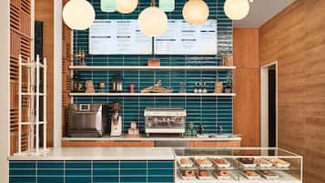A coffee shop interior with a menu board, espresso machine, and a display case with pastries.