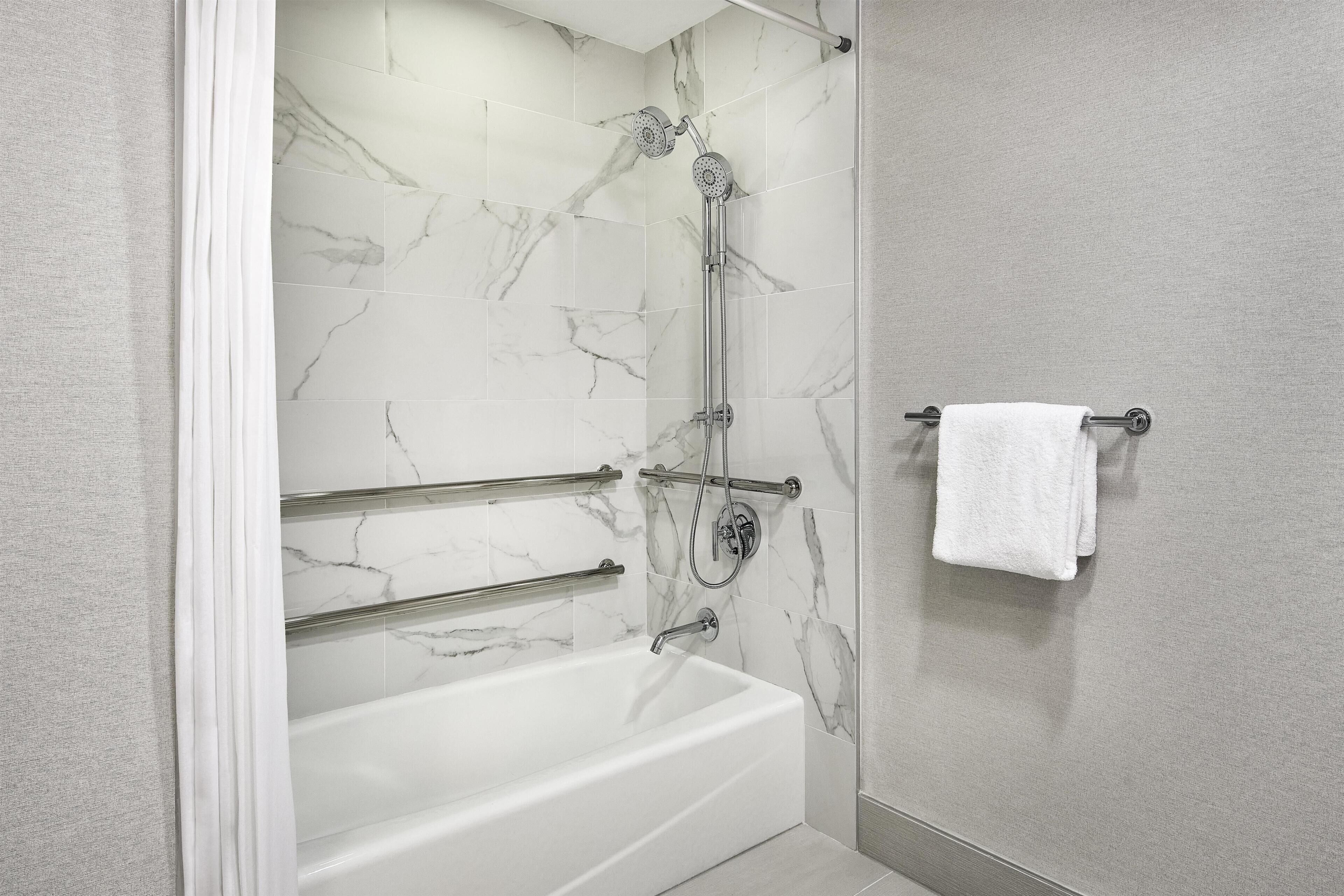Un baño moderno con pared de ducha de mármol, una bañera y un perchero para toallas.