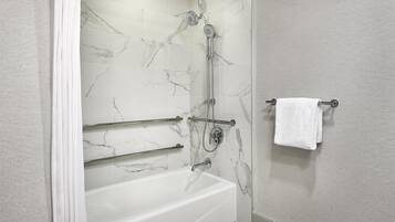Un baño moderno con pared de ducha de mármol, una bañera y un perchero para toallas.