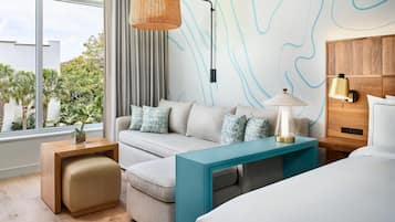 Una habitación de hotel moderna con sofá, una mesita, una lámpara y una cama.
