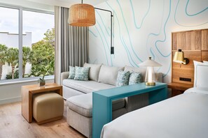 A modern hotel room with a sofa, a small table, a lamp, and a bed. - Faro Blanco Resort Marathon Florida Keys, Curio by Hilton (Marathon)