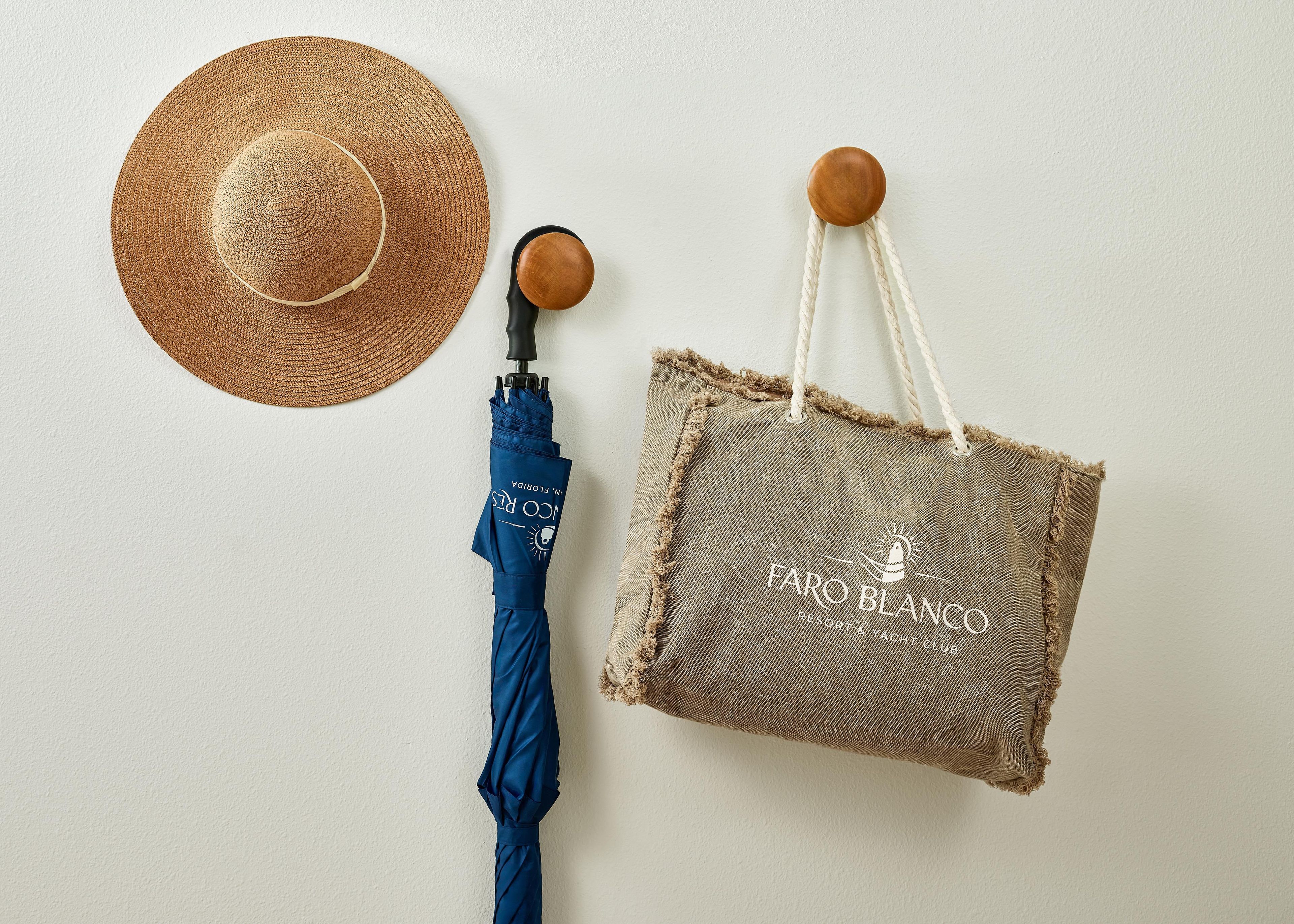 A straw hat, a blue umbrella, and a burlap tote bag with a logo.