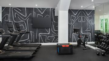 A gym with treadmills, a stationary bike, and dumbbells.