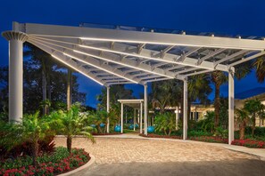 A covered outdoor area with a paved walkway, palm trees, and a building in the background. - Faro Blanco Resort Marathon Florida Keys, Curio by Hilton (Marathon)