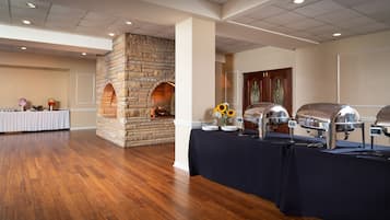 A buffet setup with a stone fireplace, a table with plates, and a grill.